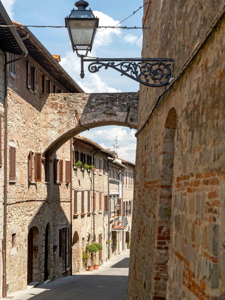 Scorcio del centro storico in pietra di Montepulciano con arco e lanterna antica.