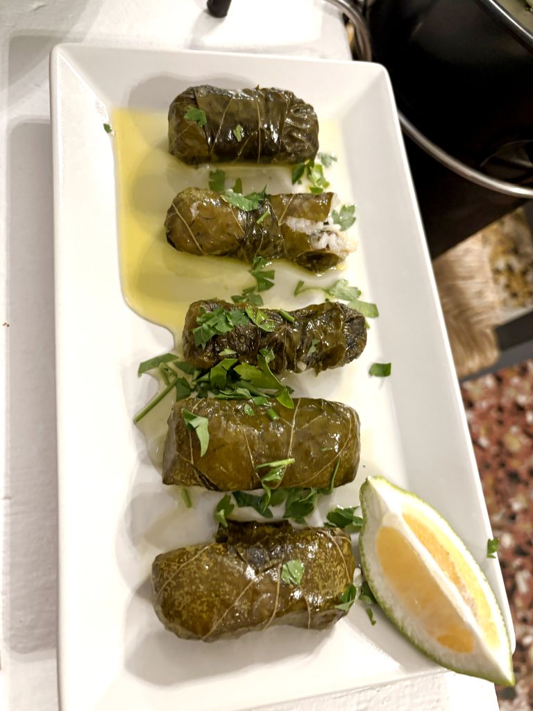 Dolmadakia greci serviti con olio d’oliva e limone su piatto tradizionale.