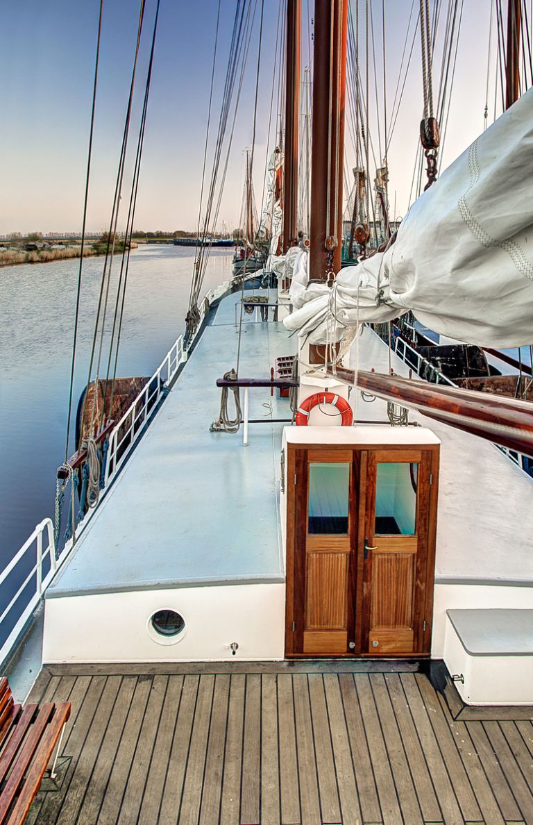 Nave a vela attraccata lungo un molo con vele bianche e cordame.