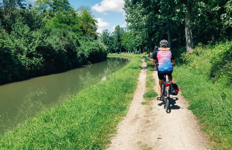 Cyclist on a bike path next to a canal, Rhône route, France.