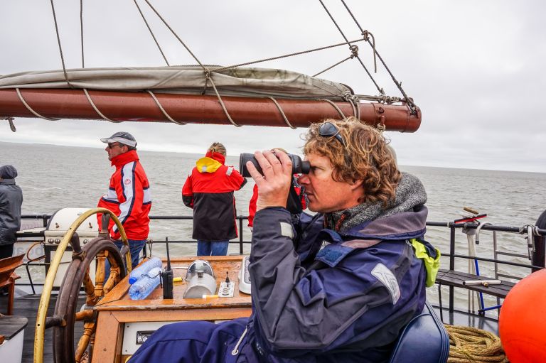 Persone sul ponte esterno a bordo di una nave a vela che osservano il panorama nel Mare del Nord, Olanda.
