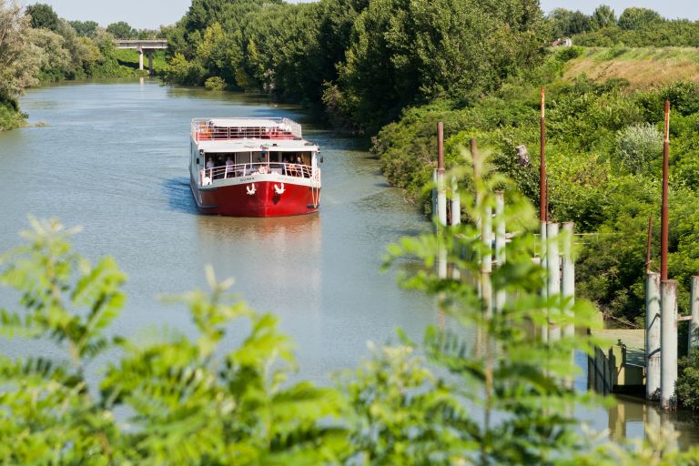 Barca Ave Maria in navigazione lungo il fiume tra il verde e la campagna