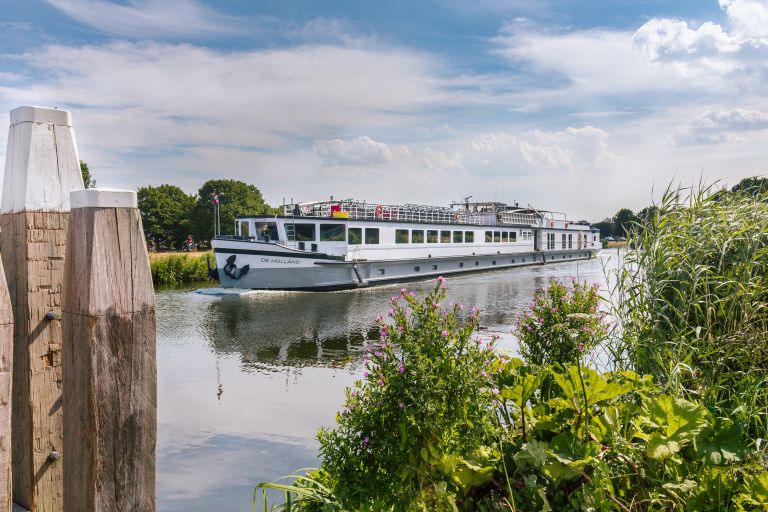 Nave da crociera fluviale naviga in un canale nelle campagne dei Paesi Bassi