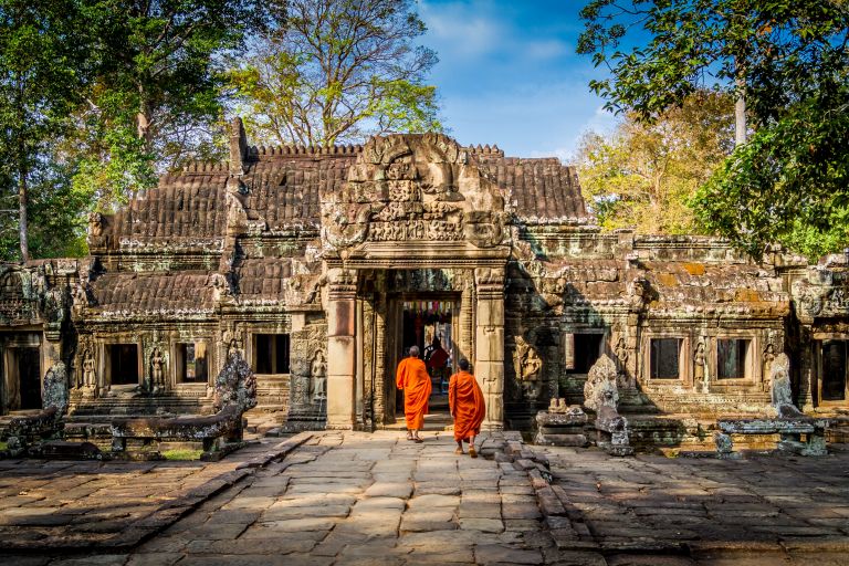 Monaci buddisti in abito arancione che varcano il tempio Preah Khan nel Parco Archeologico di Angkor, Cambogia