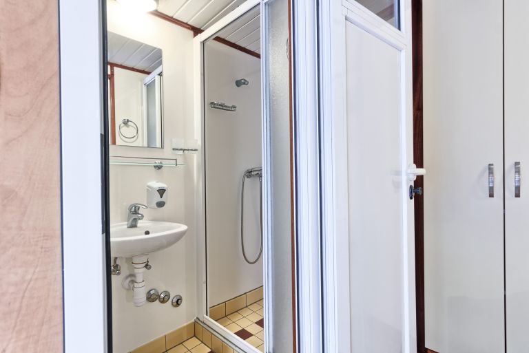Bagno con doccia e piastrelle bianche su una barca da crociera.