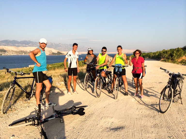 Group of cyclists resting on a beach on the Dalmatian coast, bike and boat trips