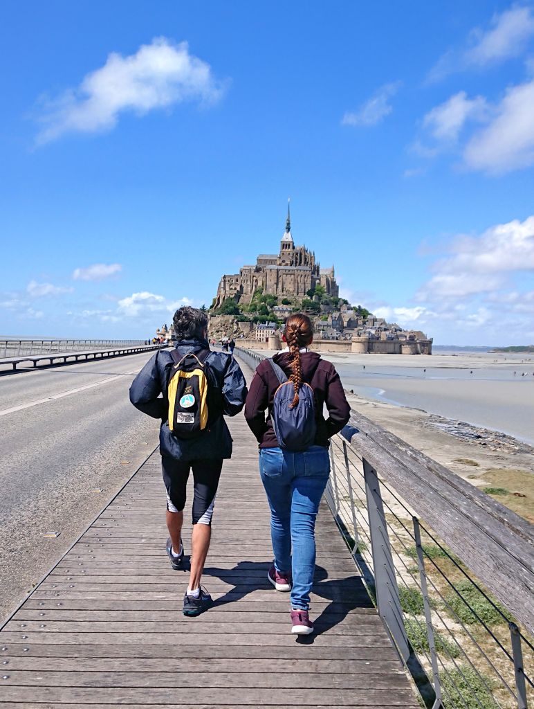 Turisti a piedi sulla passerella che conduce a Mont-Saint-Michel, Normandia.