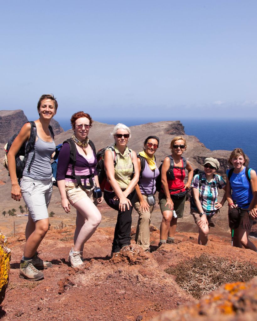 Vacanze di gruppo Girolibero, gruppo di escursionisti in posa su un terreno roccioso con vista panoramica sul mare.