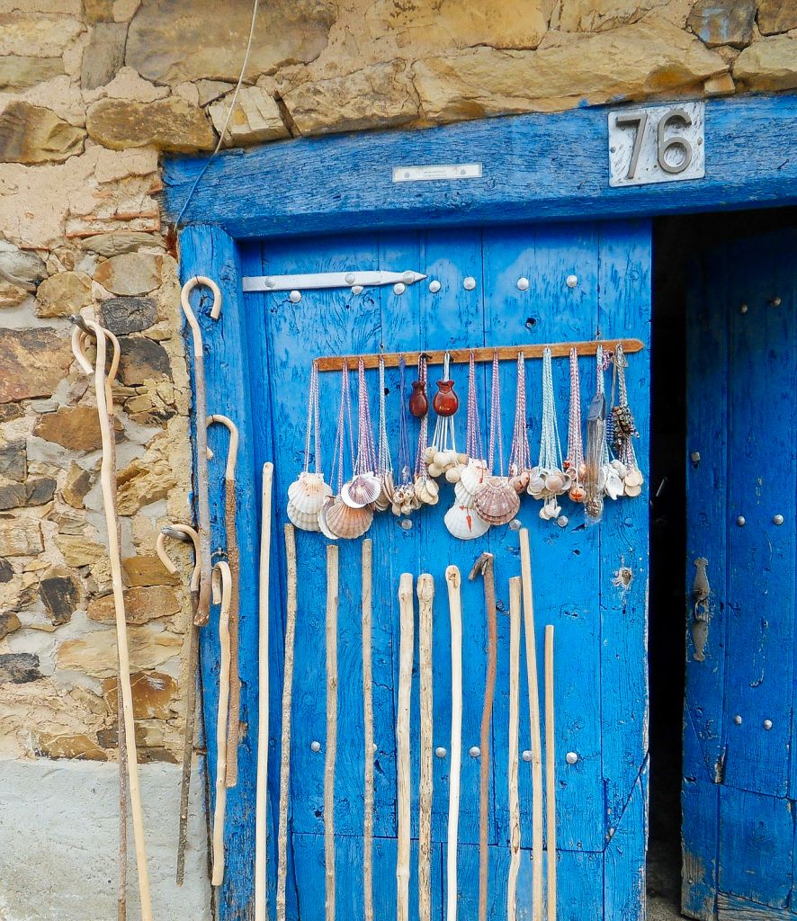 Porta blu con conchiglie, bastoni e simboli legati al pellegrinaggio di Santiago.