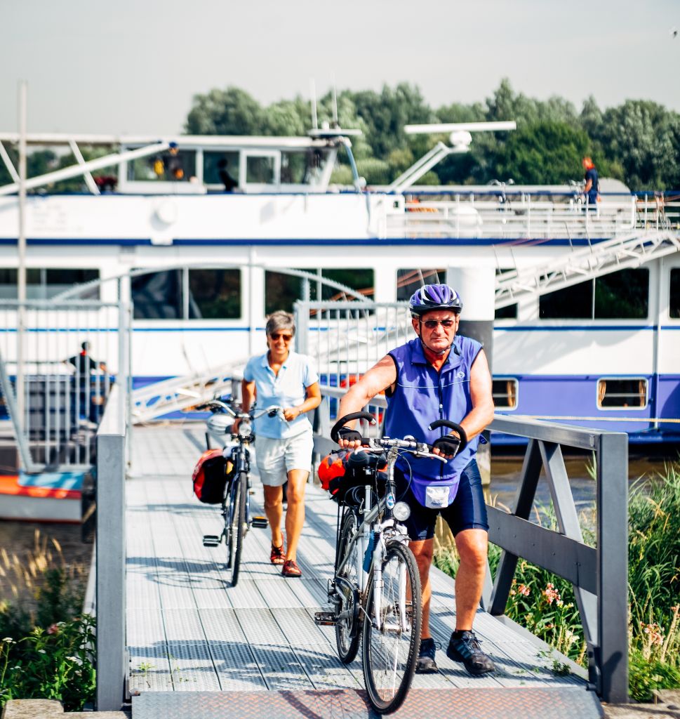 Gruppe von Radfahrern auf einem Radweg in der Nähe eines niederländischen Kanals mit Booten.