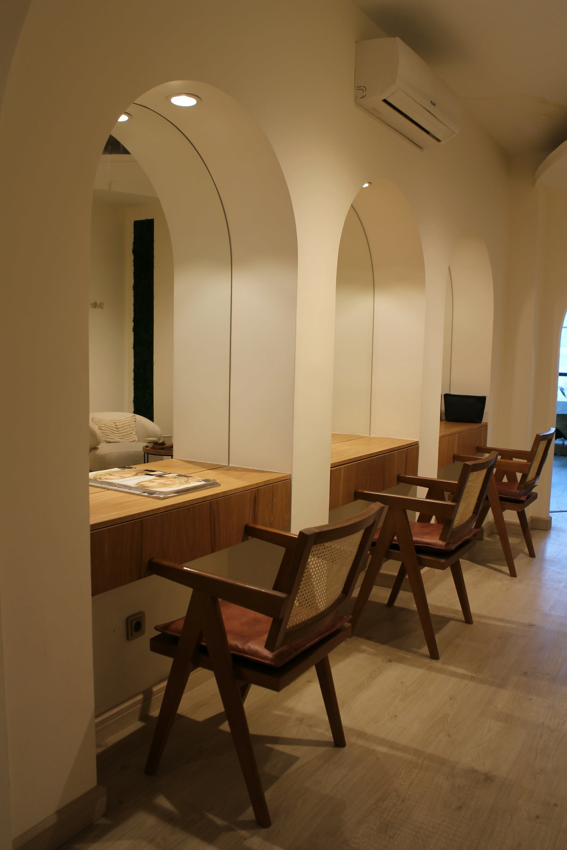 Calm clinic interior with cream arched alcoves, wooden chairs and warm neutral lighting