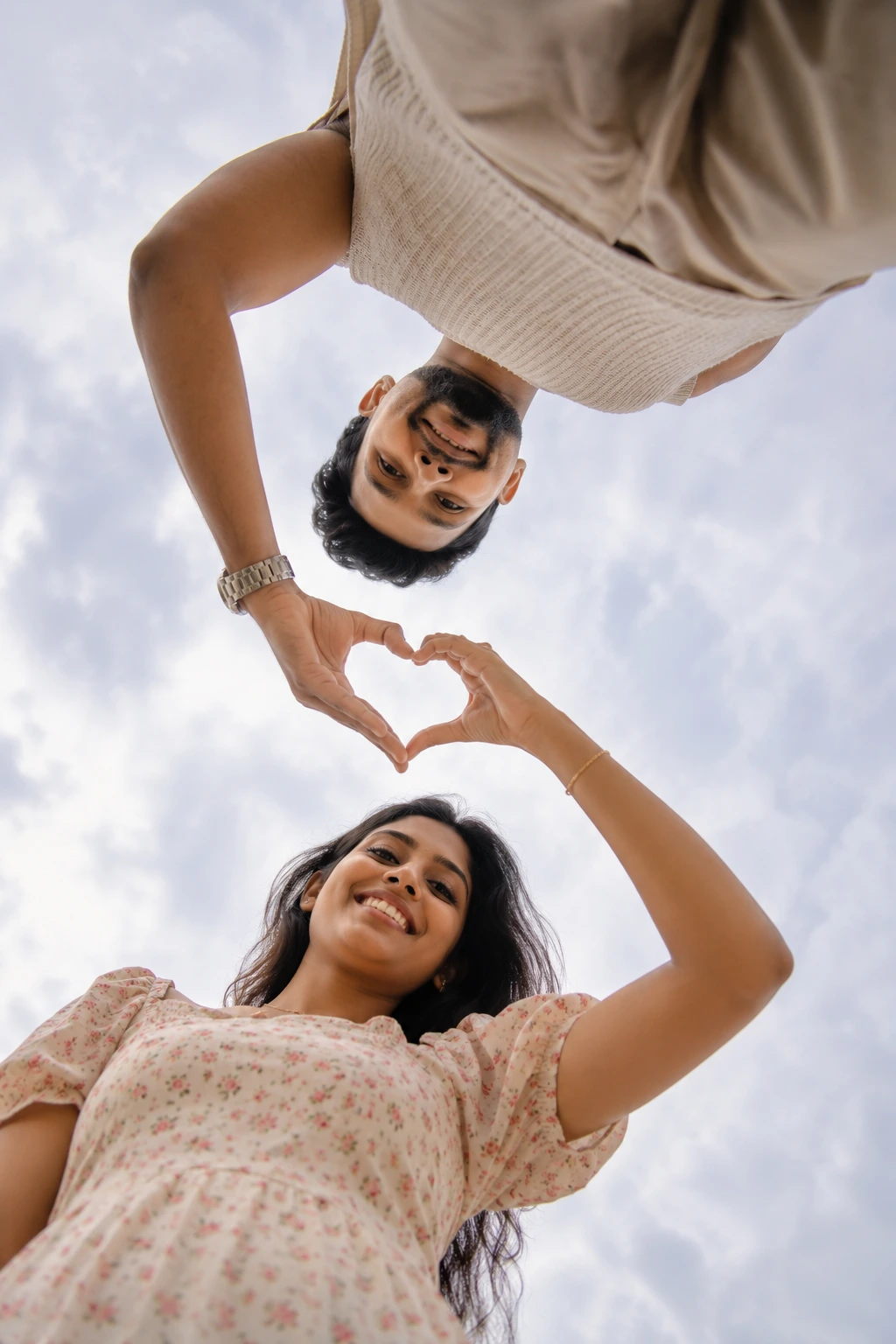 Heart-shaped gesture under cloudy sky