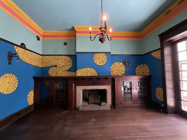 Blue room with fireplace, blue walls and yellow artwork