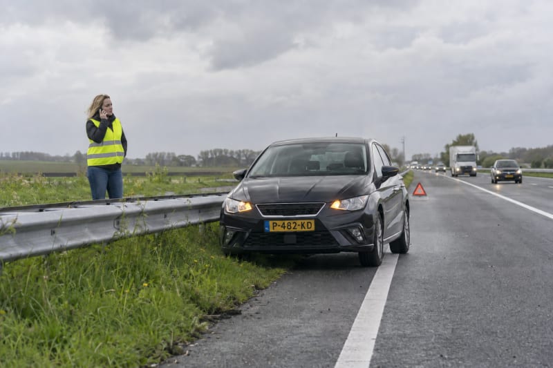 Vrouw met autopech langs de snelweg belt pechhulp
