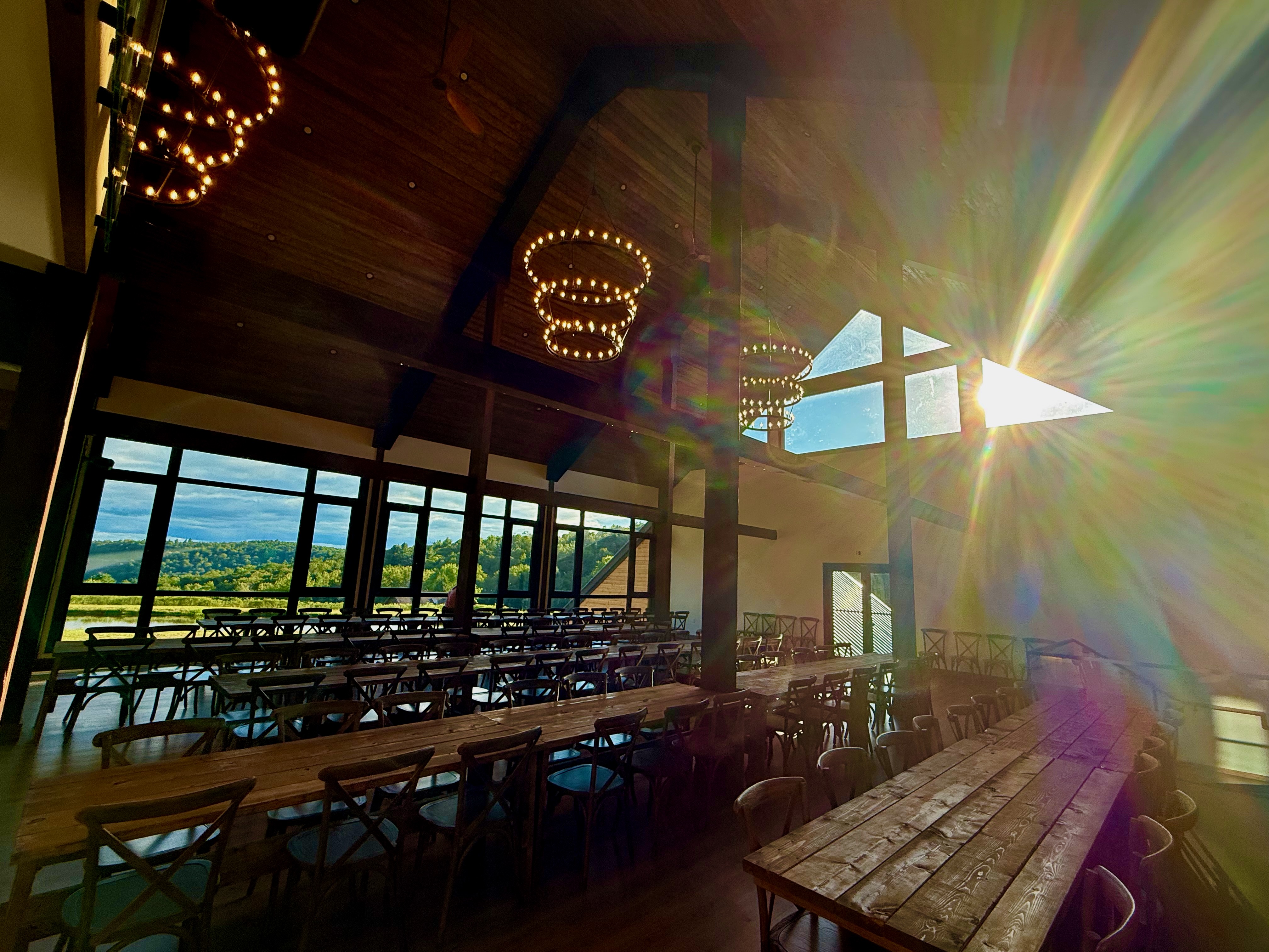 Barn interior with dramatic sunburst through windows at Mountain Meadows Catskills wedding venue