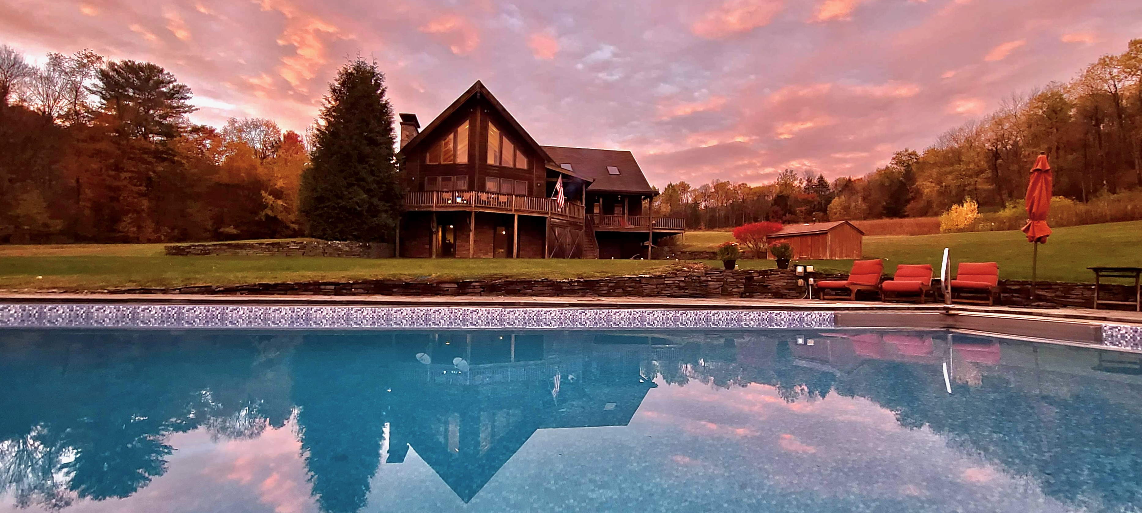 Mountain Meadows chalet reflected in heated pool at pink sunset Catskills wedding venue and vacation rental