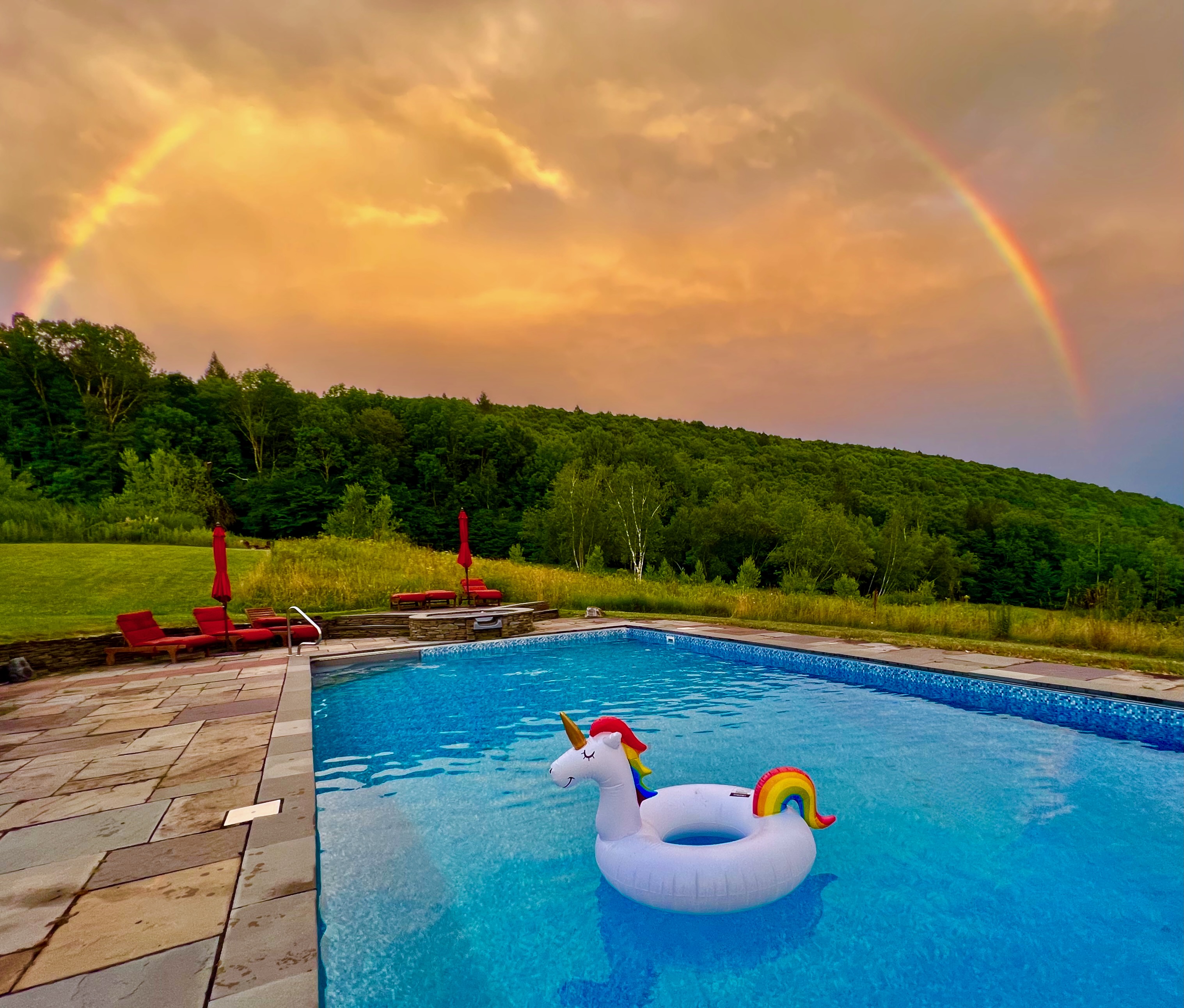 Rainbow over pool with unicorn float at Mountain Meadows private Catskills resort Long Eddy NY