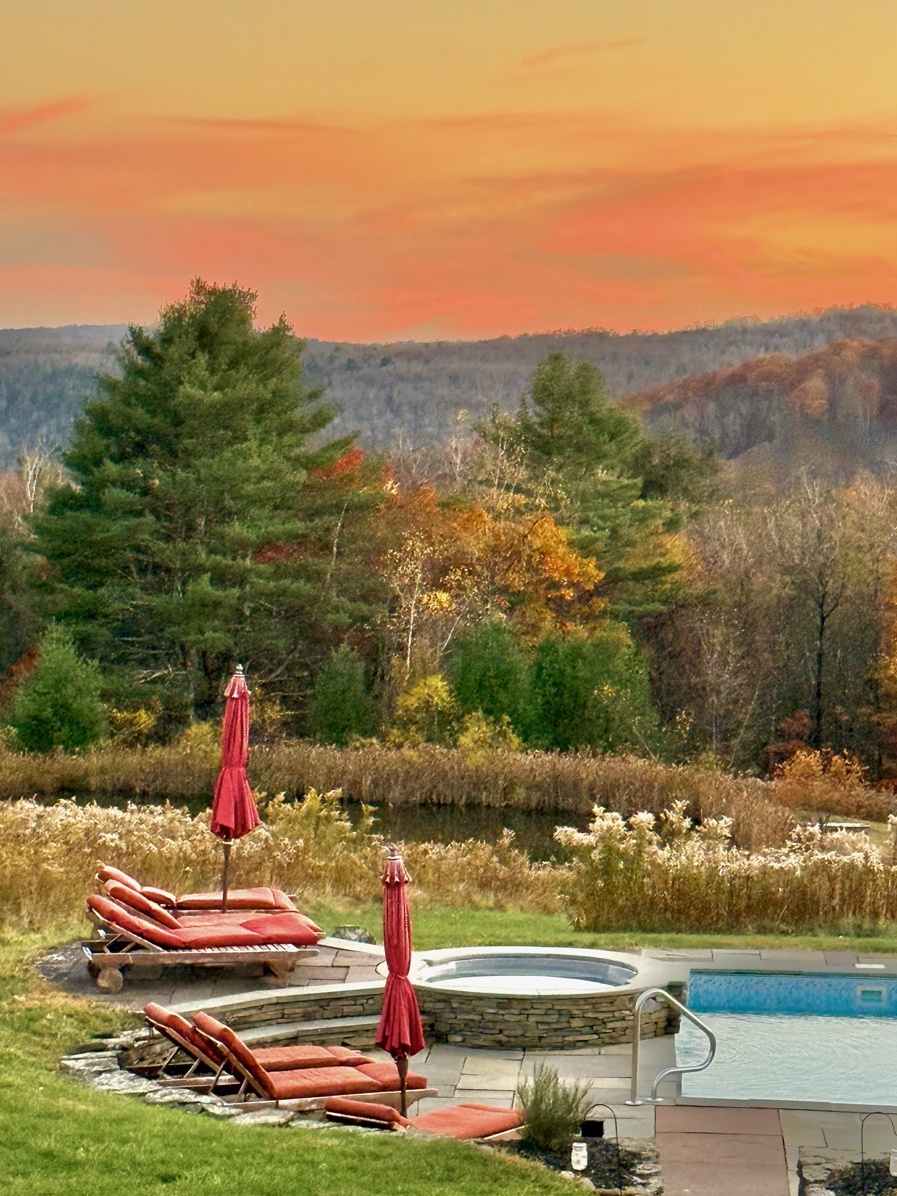 Pool spa and lounge chairs at sunset with fall foliage and mountain views at Mountain Meadows private Catskills resort Long Eddy NY