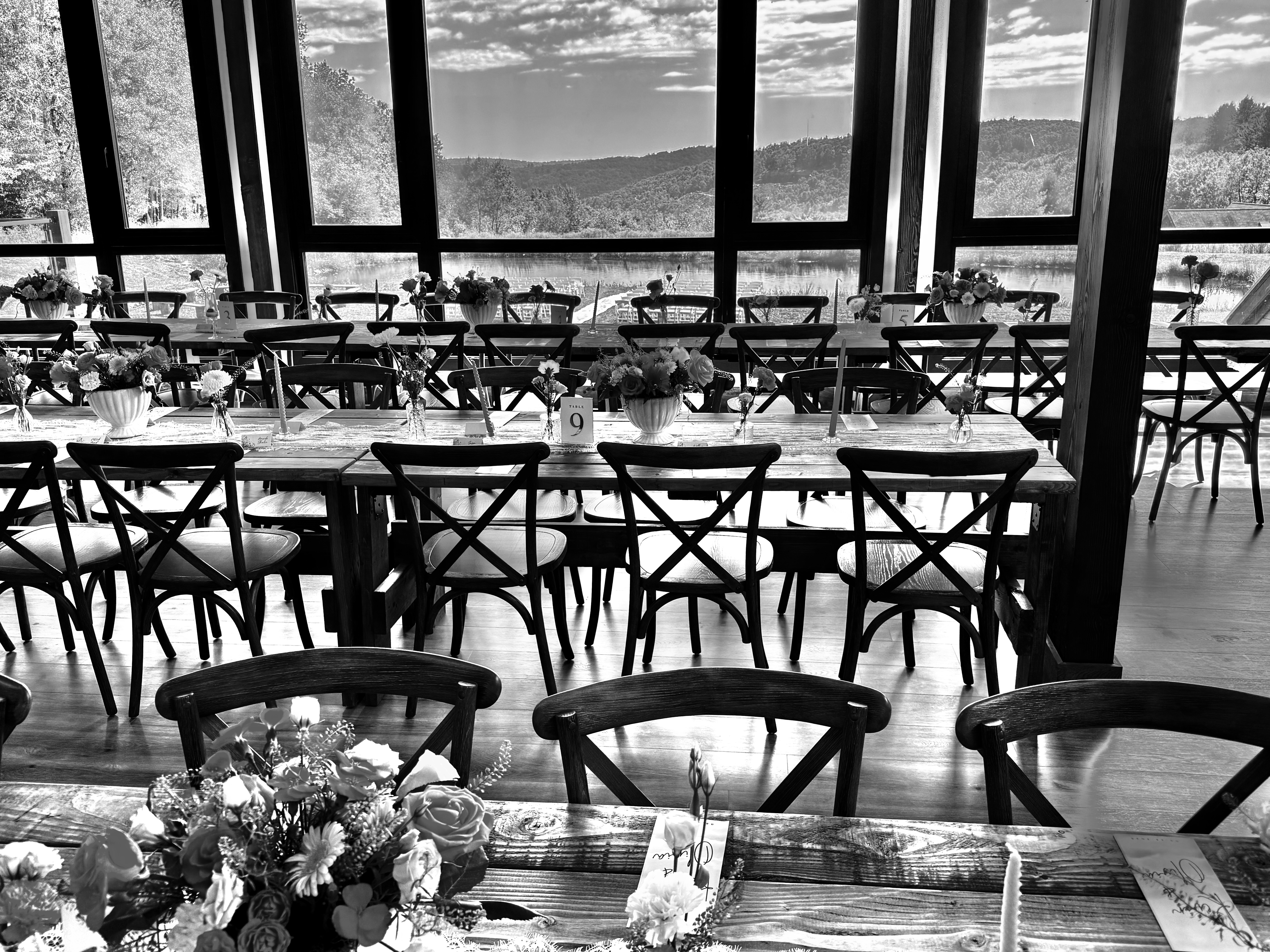 Black and white barn reception tables with mountain view through windows at Mountain Meadows Catskills wedding venue