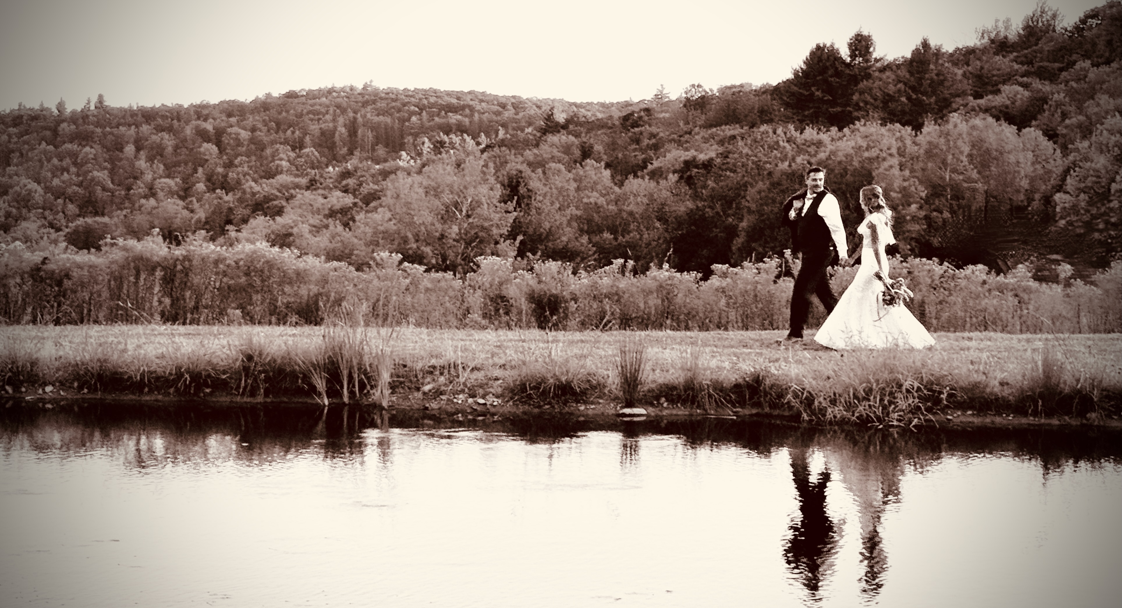 Bride and groom walking by pond at Mountain Meadows Catskills destination wedding venue Long Eddy NY