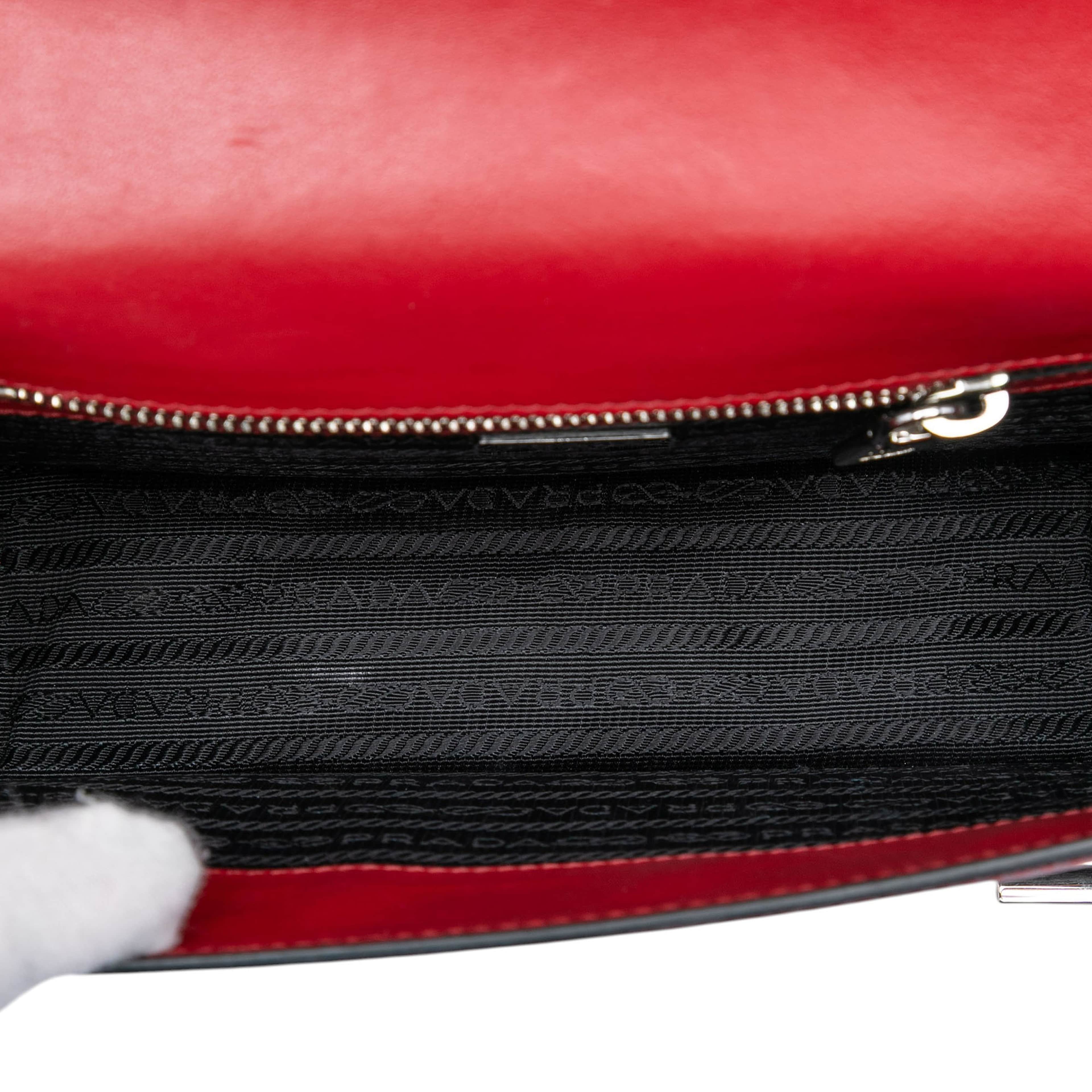 Prada Saffiano Double Turn Lock Top Handle Bag, från Luxclusif, i färgen red. Klicka för att öppna bilden i stort format