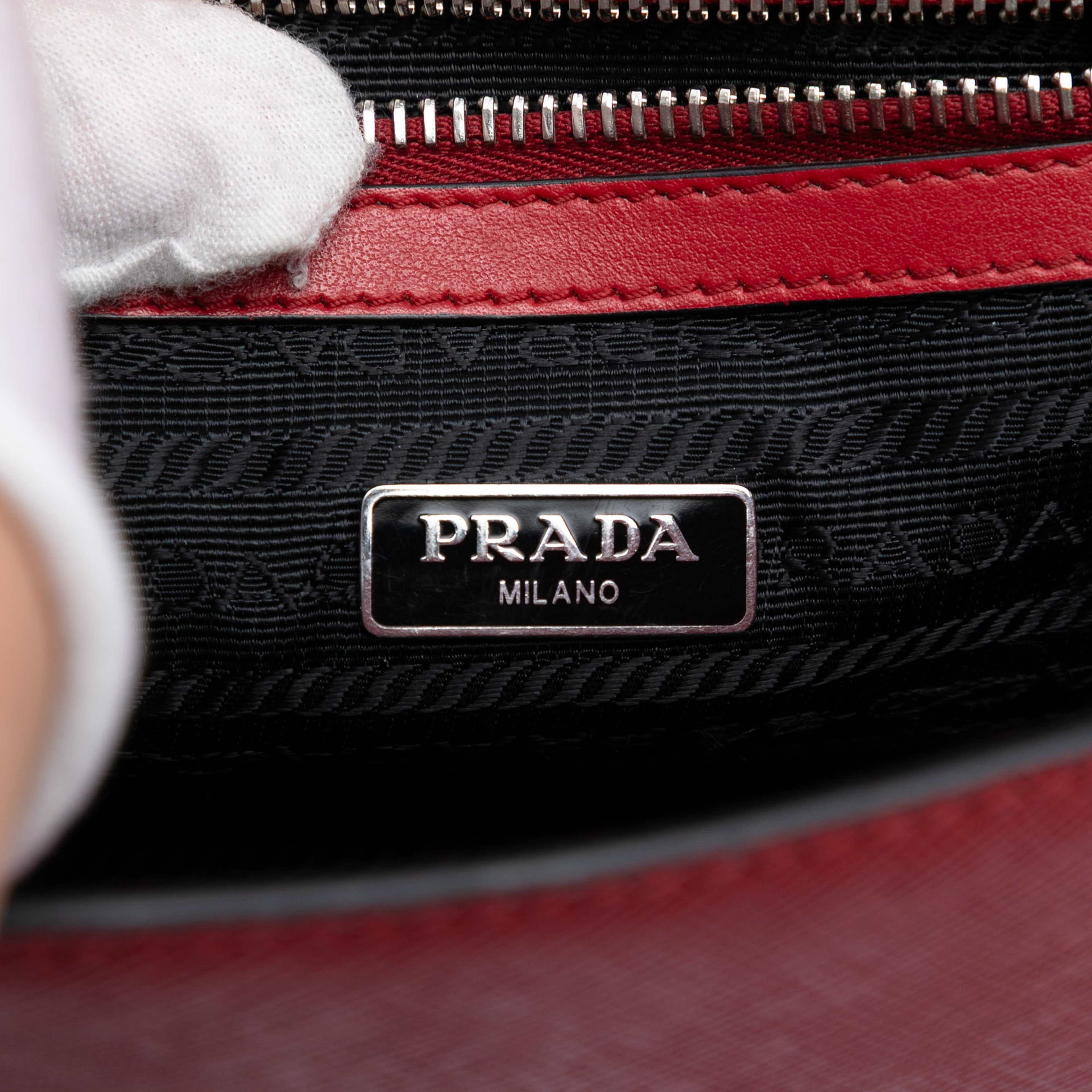 Prada Saffiano Double Turn Lock Top Handle Bag, från Luxclusif, i färgen red. Klicka för att öppna bilden i stort format