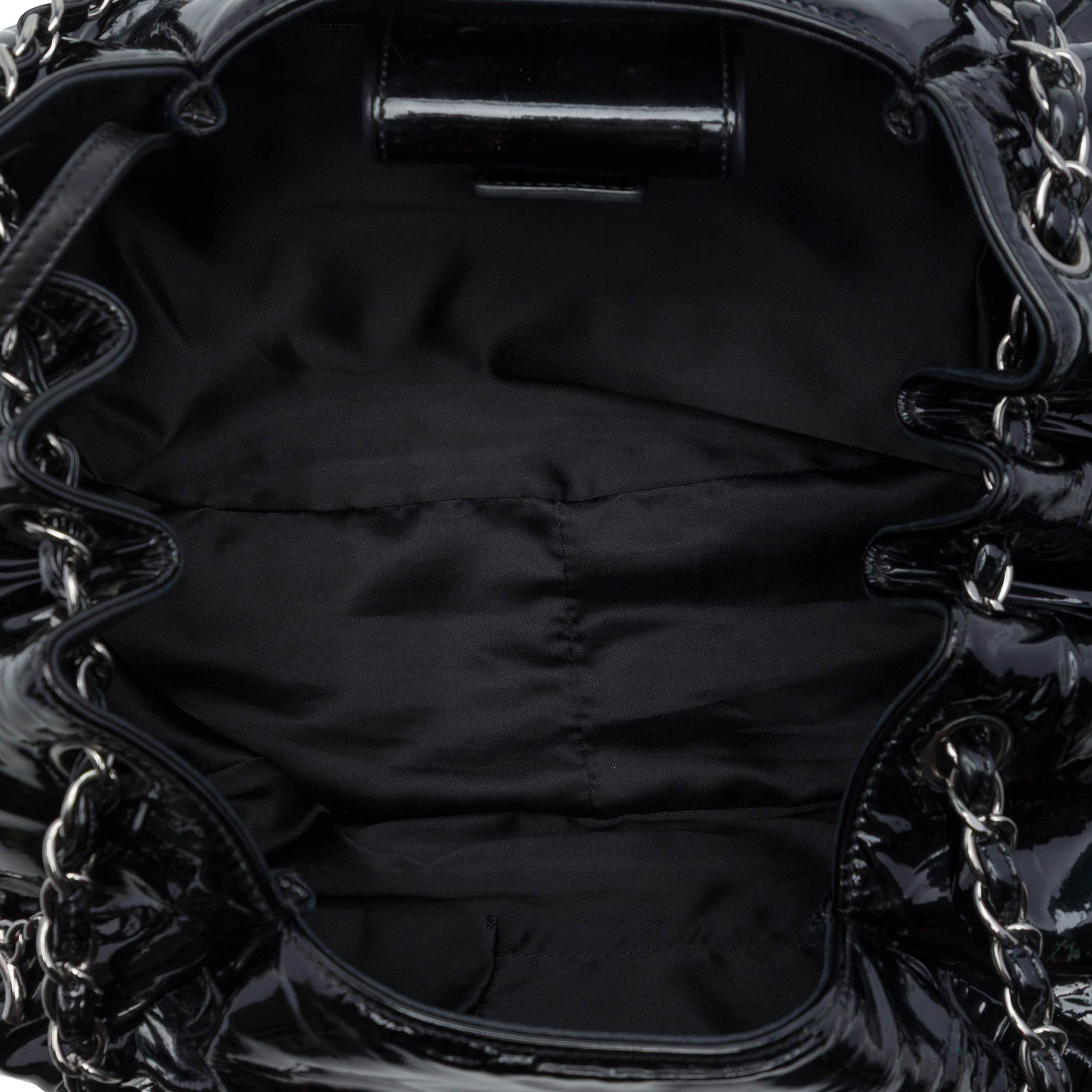 Chanel Patent Accordion Camellia Tote, från Luxclusif, i färgen svart. Klicka för att öppna bilden i stort format
