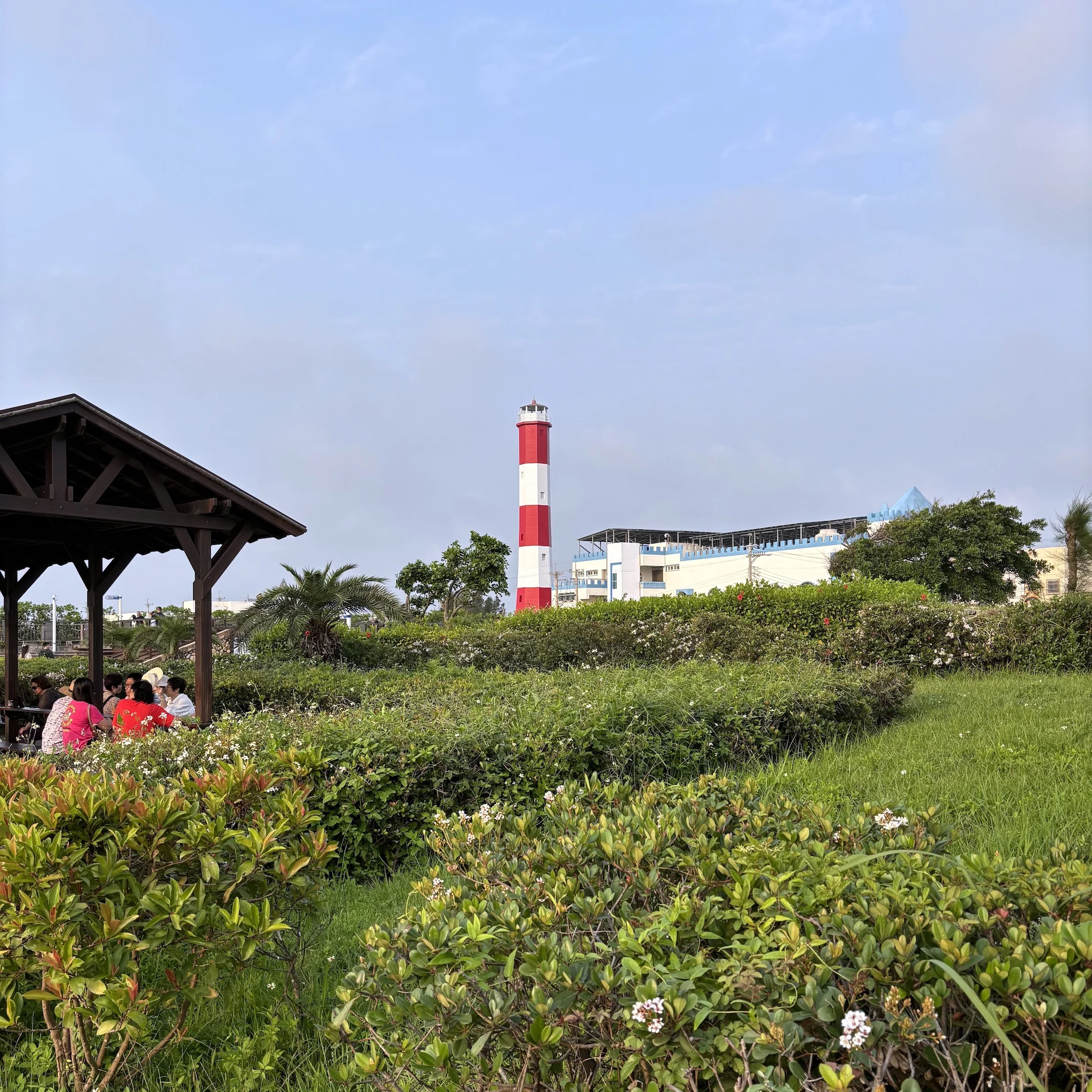 A lighthouse in the distance of a grassy area.