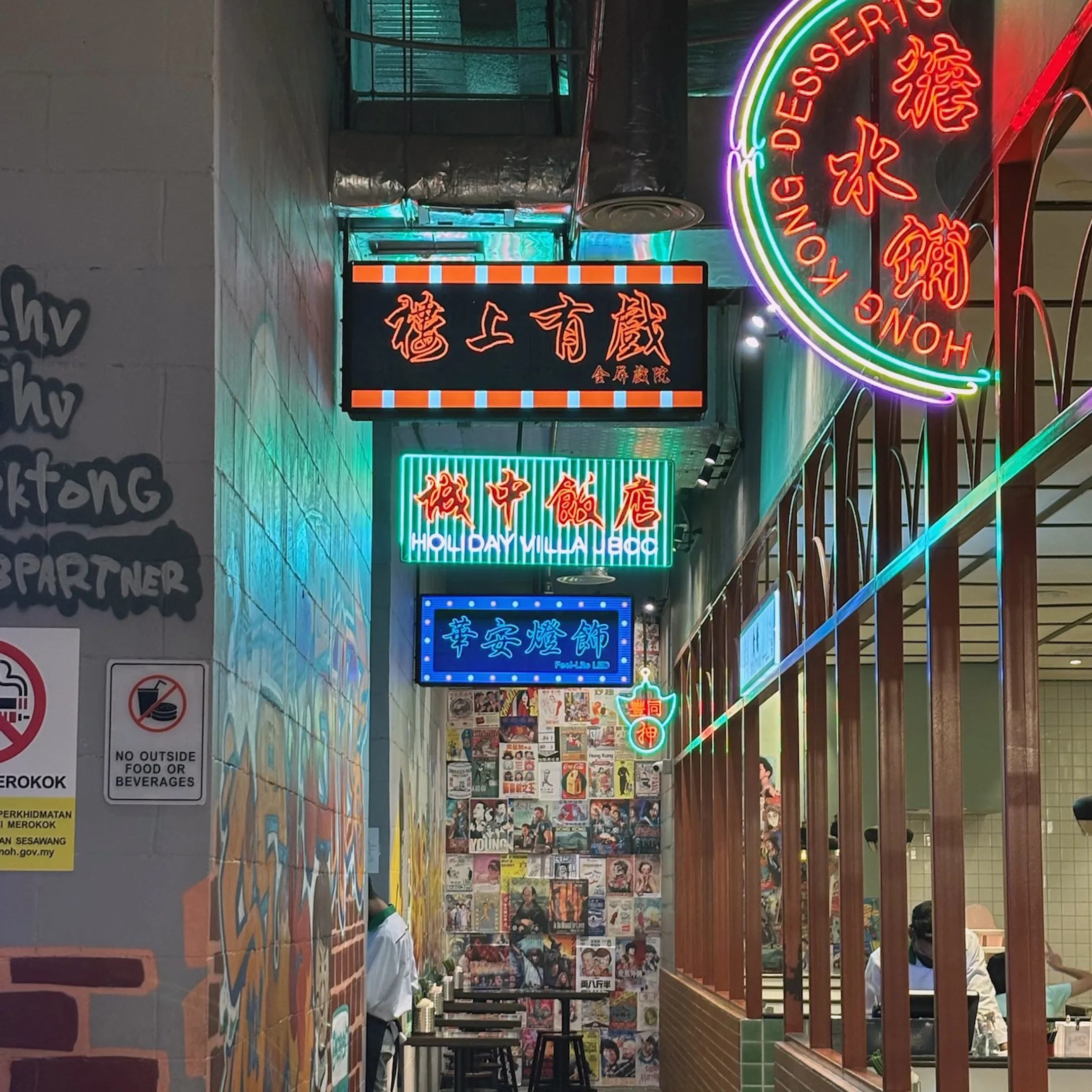 A long hallway with neon signs and a man walking down the hallway.
