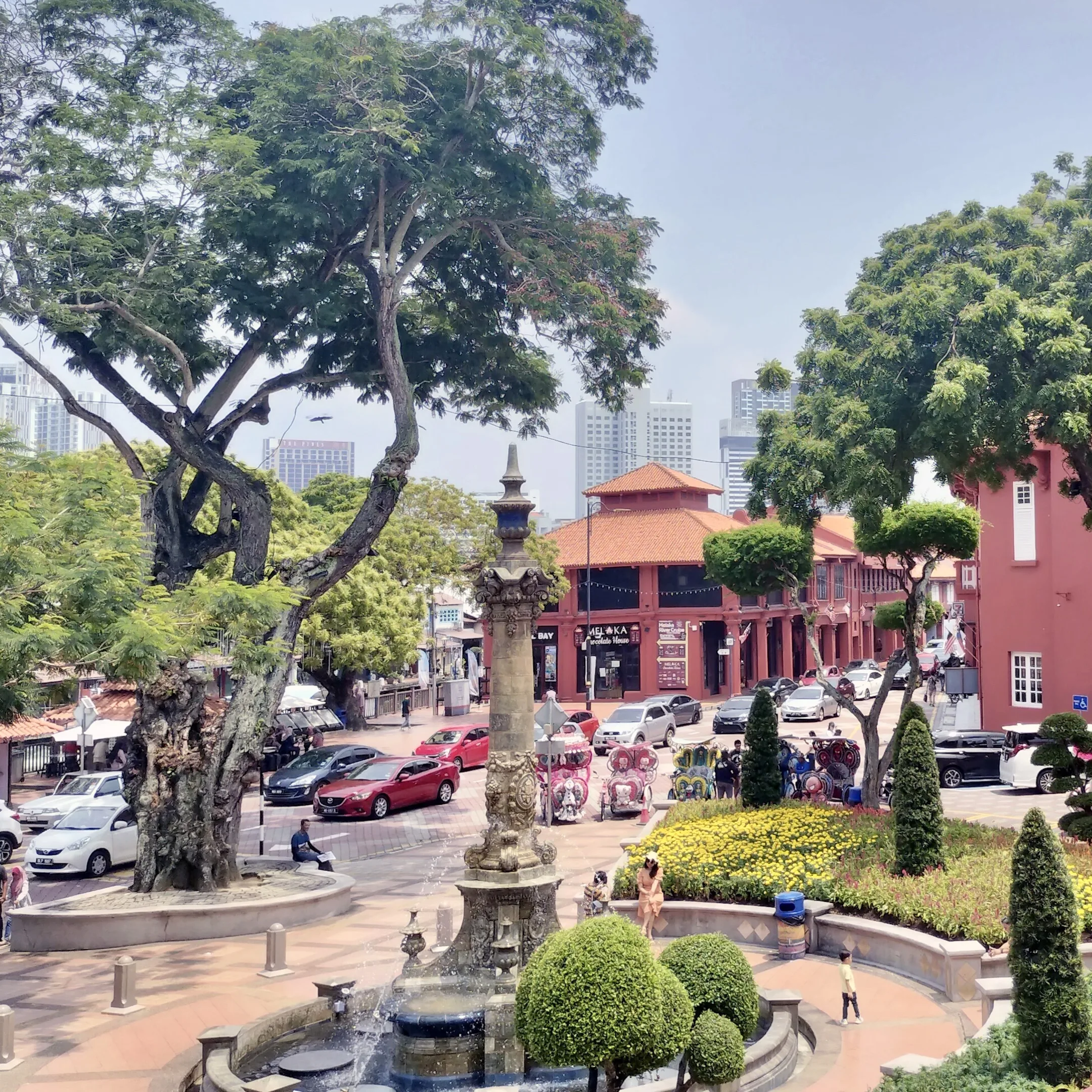 A fountain in a plaza with a tree in the middle.