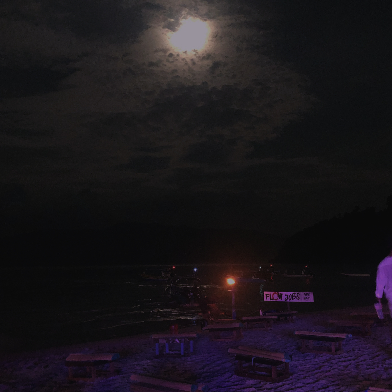 A man standing on a beach at night.