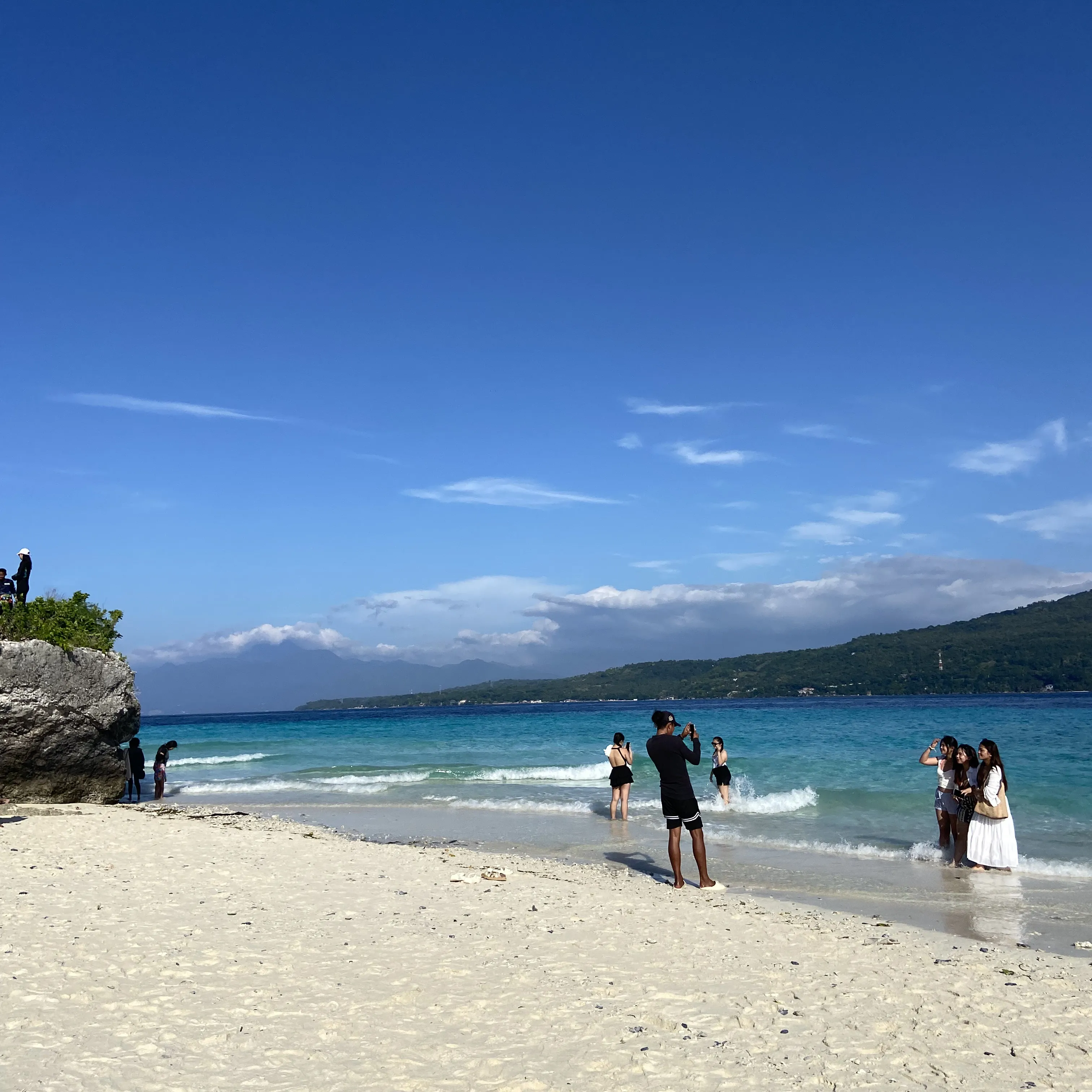 People are walking on the beach near the water.