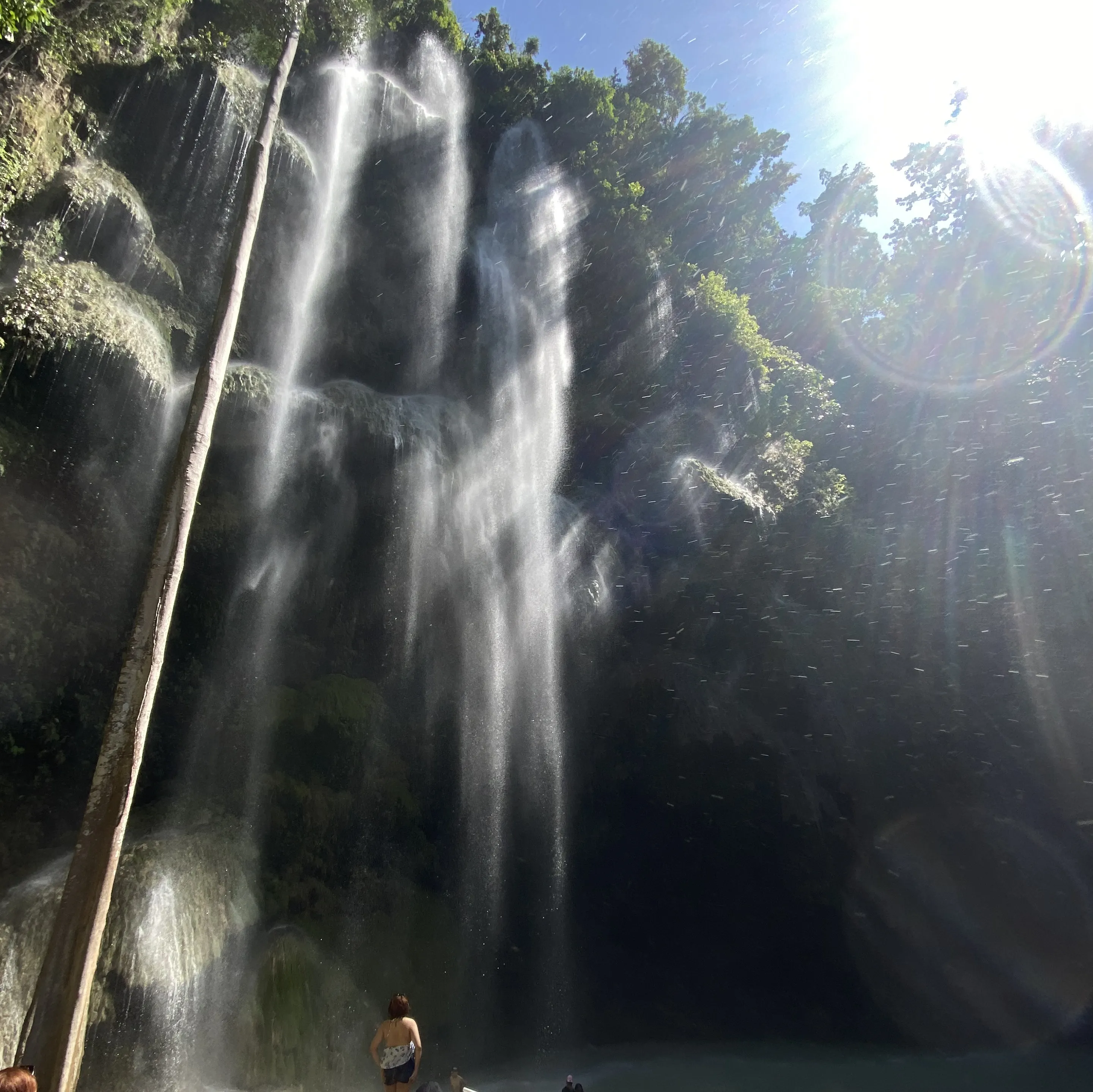 A man and a woman are standing in front of a waterfall.