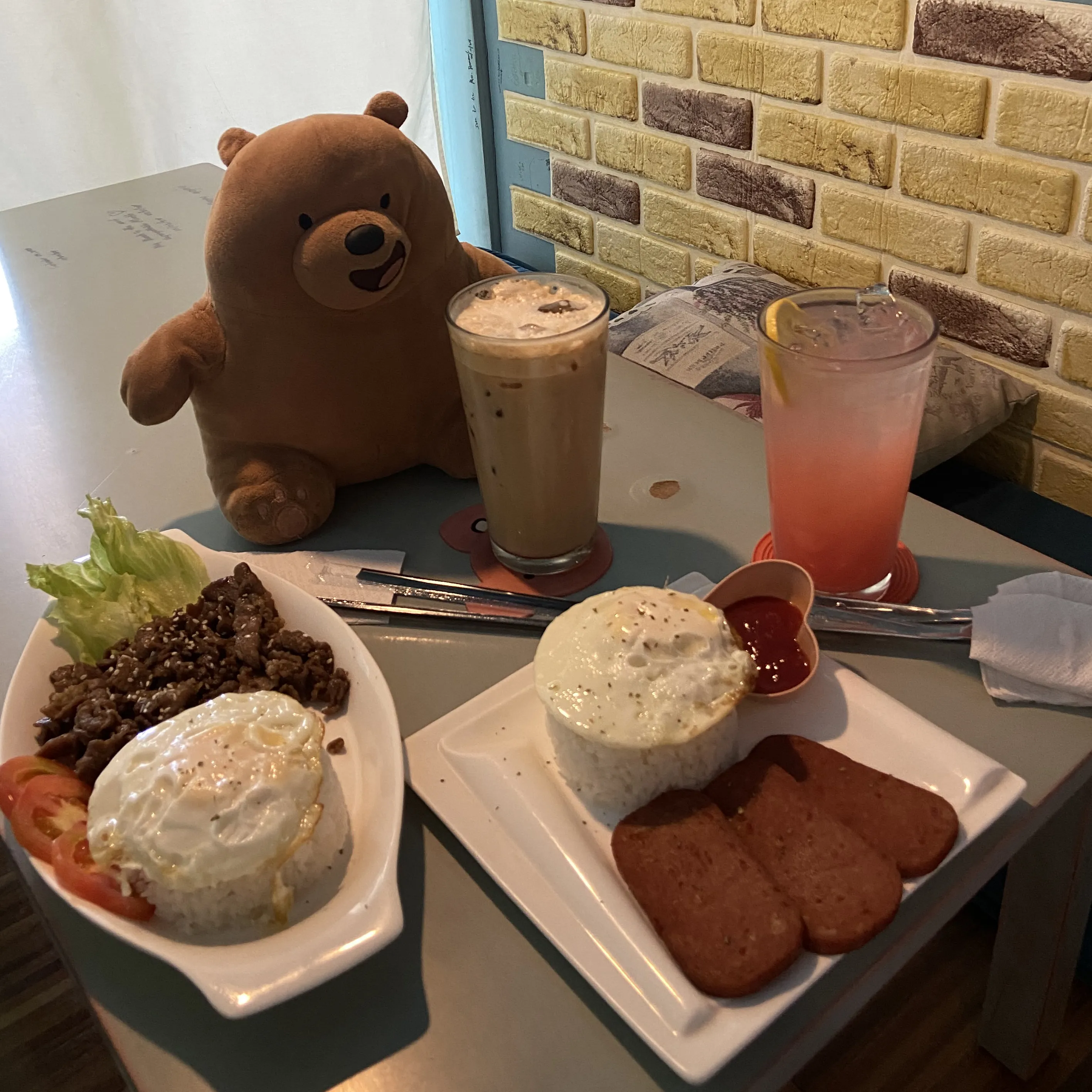 A teddy bear sitting at a table with a plate of food.