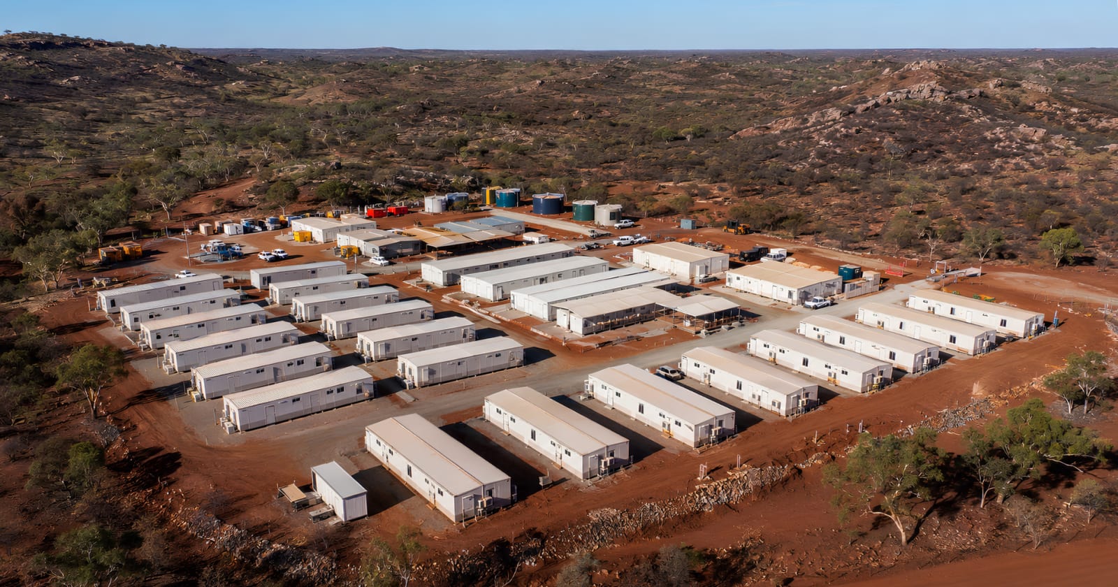 Industrial mining camp at sunset with rows of modular accommodation buildings deployed on a remote site