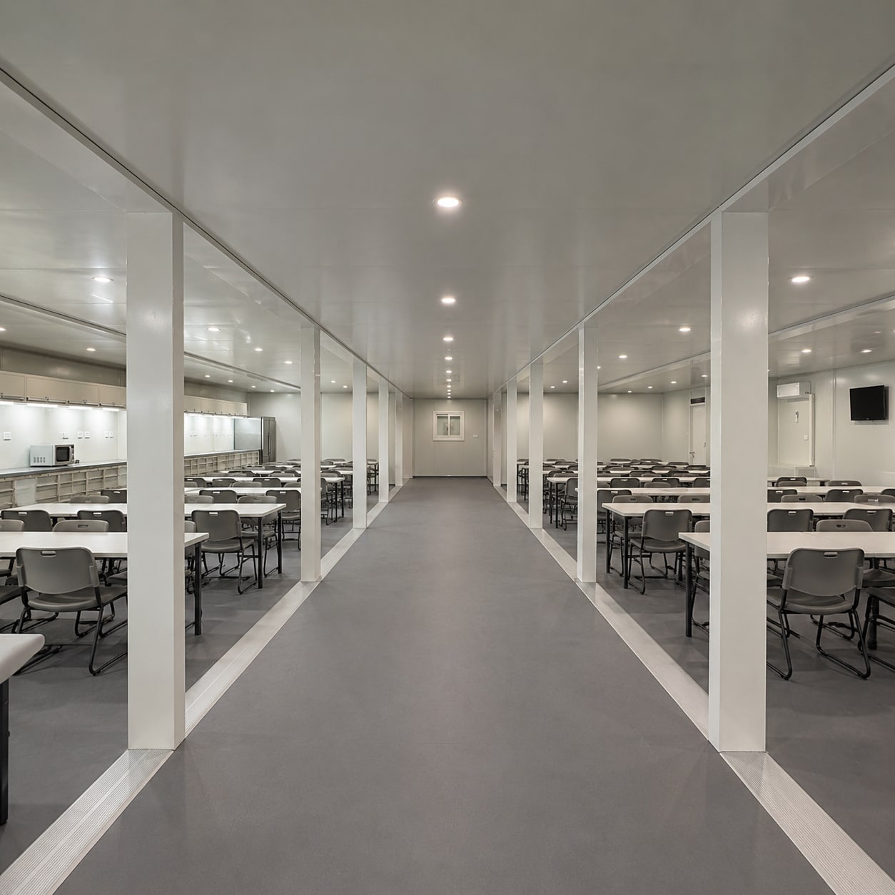 Mess hall interior in a container camp building with rows of dining tables and seating