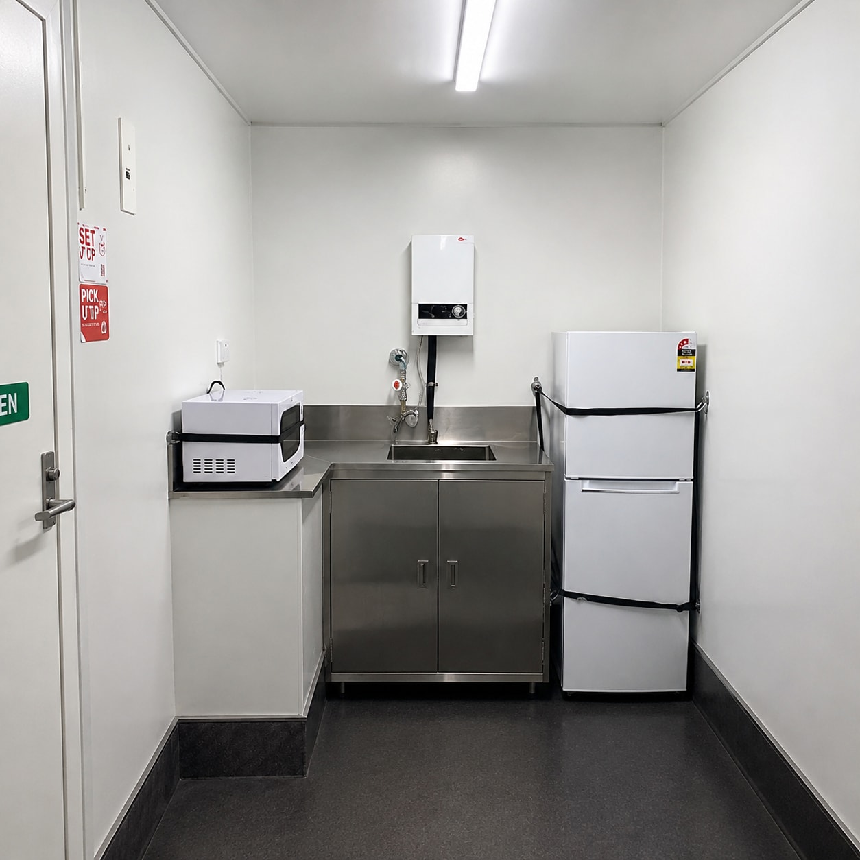 Kitchenette fitout in a container crib room with stainless bench, sink, microwave and fridge