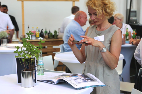 Person scannt Kocks Event-Magazin mit Handy und zeigt Interesse