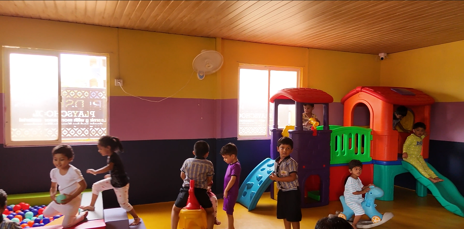 A teacher reading a book to elementary school students in a colorful classroom.