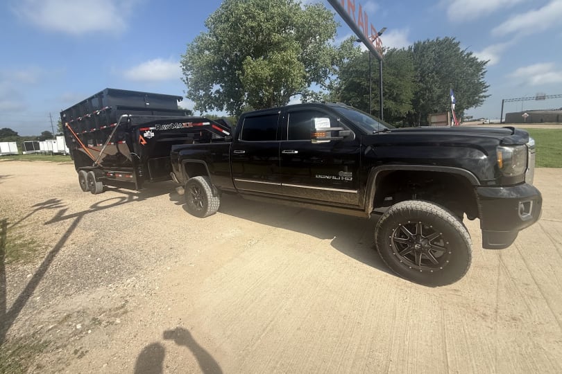 A Forging Solutions truck hauling a roll-off dump trailer for delivery