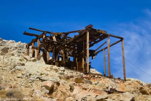 Wooden posts and structure on a desert hillside with blue sky beyond