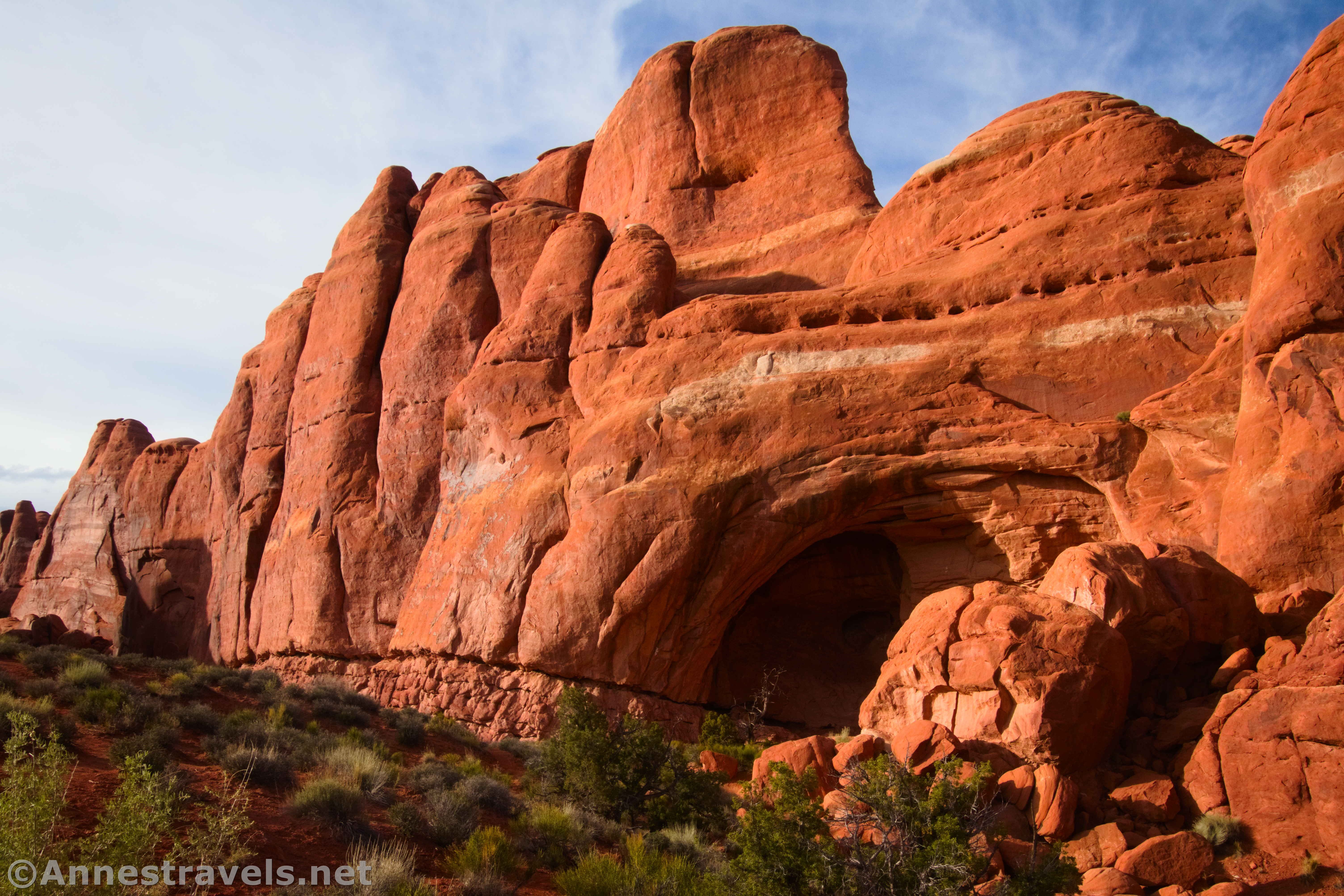 A red wall of rocks with blue sky and clouds beyond