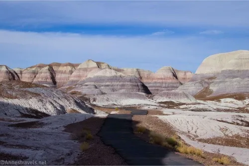 Purple striped badlands below a blue sky with clouds 