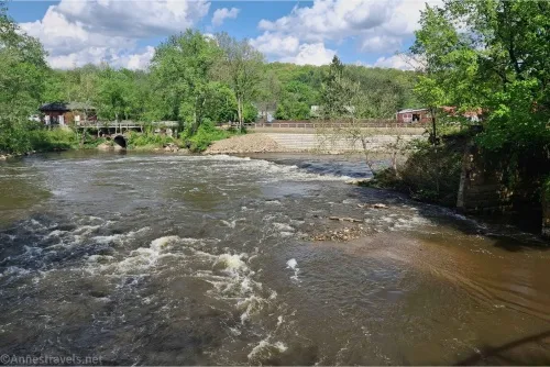 A large river among green trees and below puffy white clounds