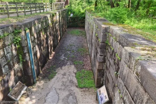 Looking into an old canal lock made of large, oblong stones 