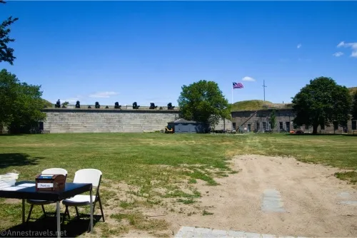 Inside Fort Independence including a table, two chairs, a flag, a path, and several cannons
