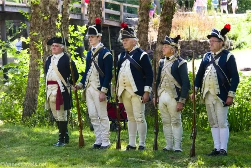 Five men dressed as though in the Continental Army stand beside North Bridge