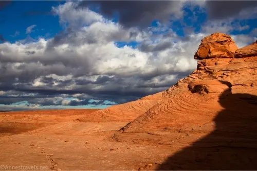 Clouds sail over and around a rock formation in the desert