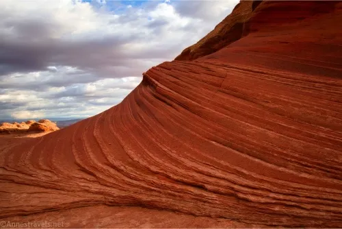 Layers of rock create stripes below white clouds