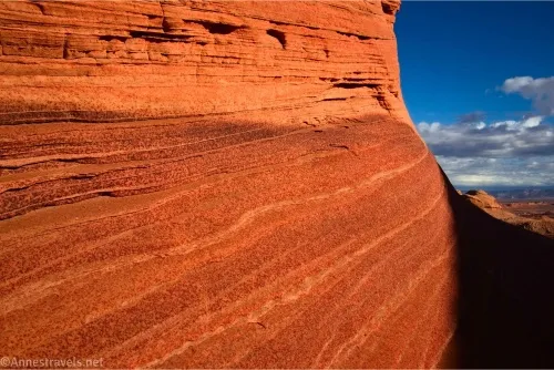 Red and yellow striped rock with blue sky and a few white clouds beyond